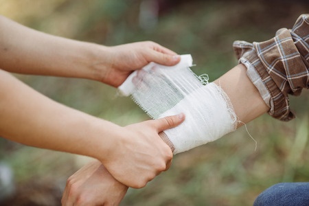 a person wrapping his friends injured arm in gauze