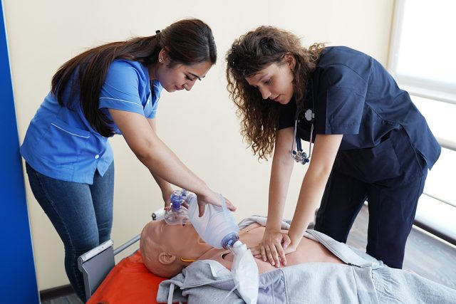 two nursing students practice BCLS and ACLS techniques on a CPR mannequin