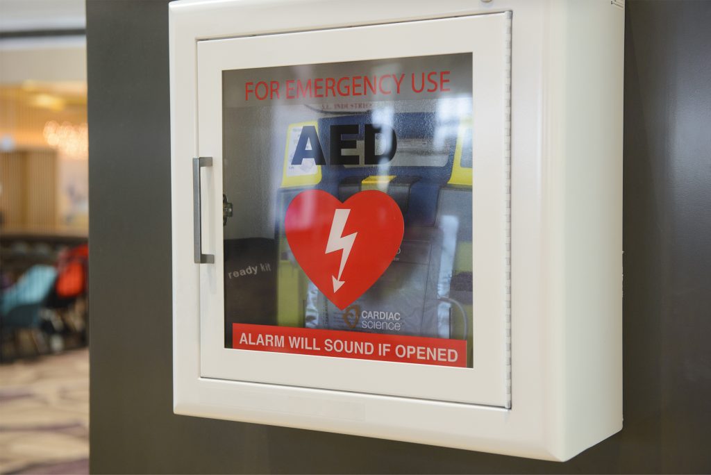 A typical AED location with the machine housed in a white box with the universal sign for AED